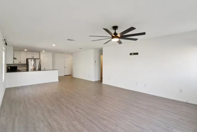 a view of an empty room with a ceiling fan and wooden floor