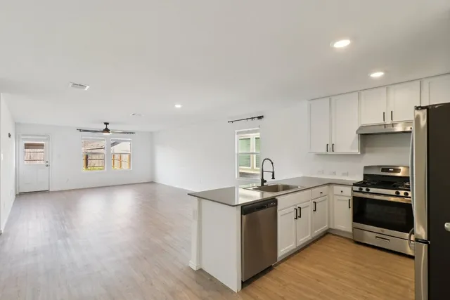 a kitchen with stainless steel appliances granite countertop a stove cabinets and wooden floor