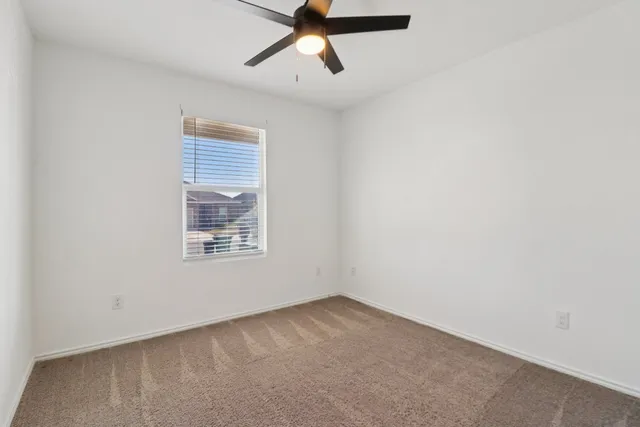 an empty room with a window and a ceiling fan