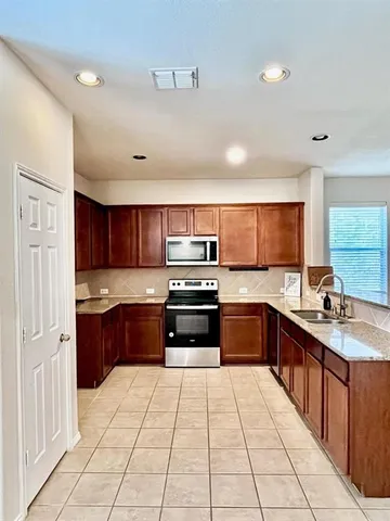 a large kitchen with stainless steel appliances kitchen island granite countertop a sink and cabinets