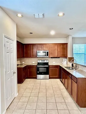 a large kitchen with stainless steel appliances granite countertop a stove and cabinets