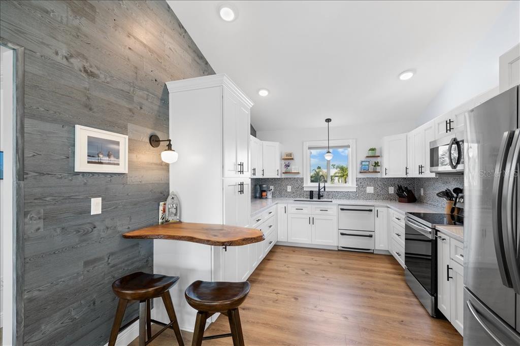 4452 Kingston Drive Hernando Beach, FL 34607 - Photo 11 of 47 a kitchen with stainless steel appliances kitchen island granite countertop a refrigerator a stove a sink dishwasher with a dining table and chairs