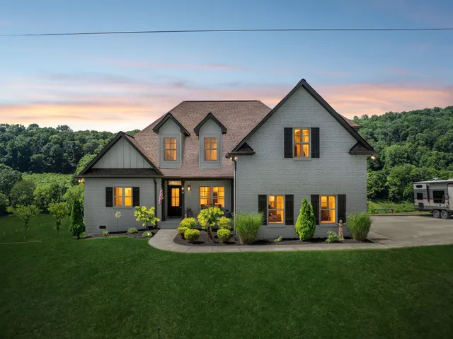 a front view of a house with a yard and green space
