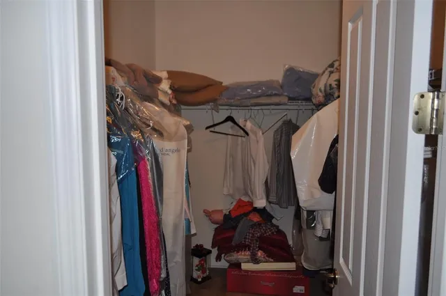a view of walk in closet with clothes and shoes