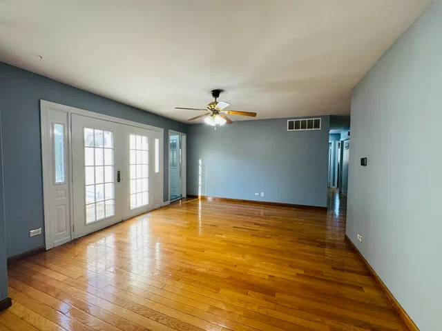 a view of an empty room with window and wooden floor
