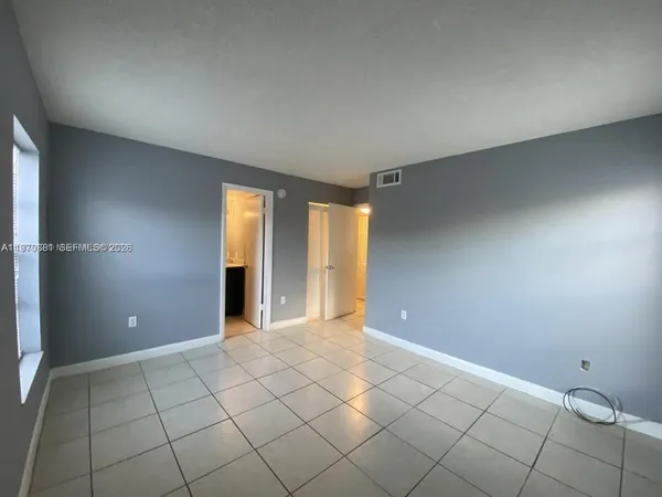 a view of an empty room with window and chandelier fan
