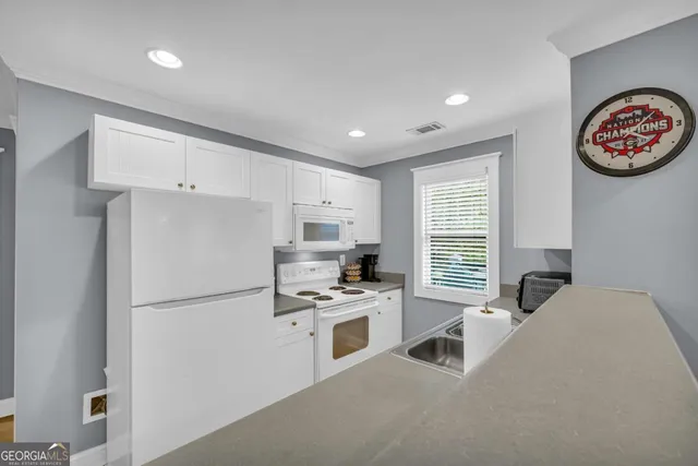 a kitchen with stainless steel appliances a refrigerator a sink a stove and white cabinets