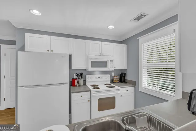 a kitchen with stainless steel appliances a refrigerator sink and white cabinets