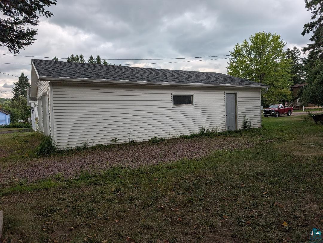 202 Thomas Street Mellen, WI 54546 - Photo 16 of 37 White horizontal vinyl siding with a single window, a side entry door, and a shingled gable roof