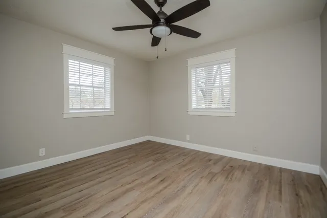 a view of an empty room with wooden floor and a window