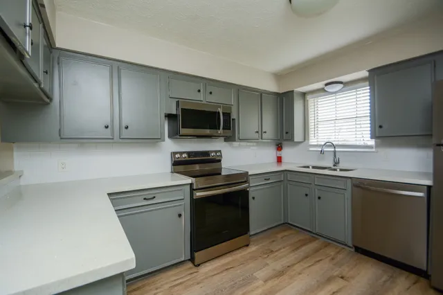 a kitchen with cabinets stainless steel appliances a sink and a window