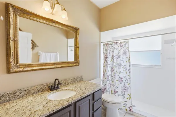 a bathroom with a granite countertop sink a toilet and a mirror