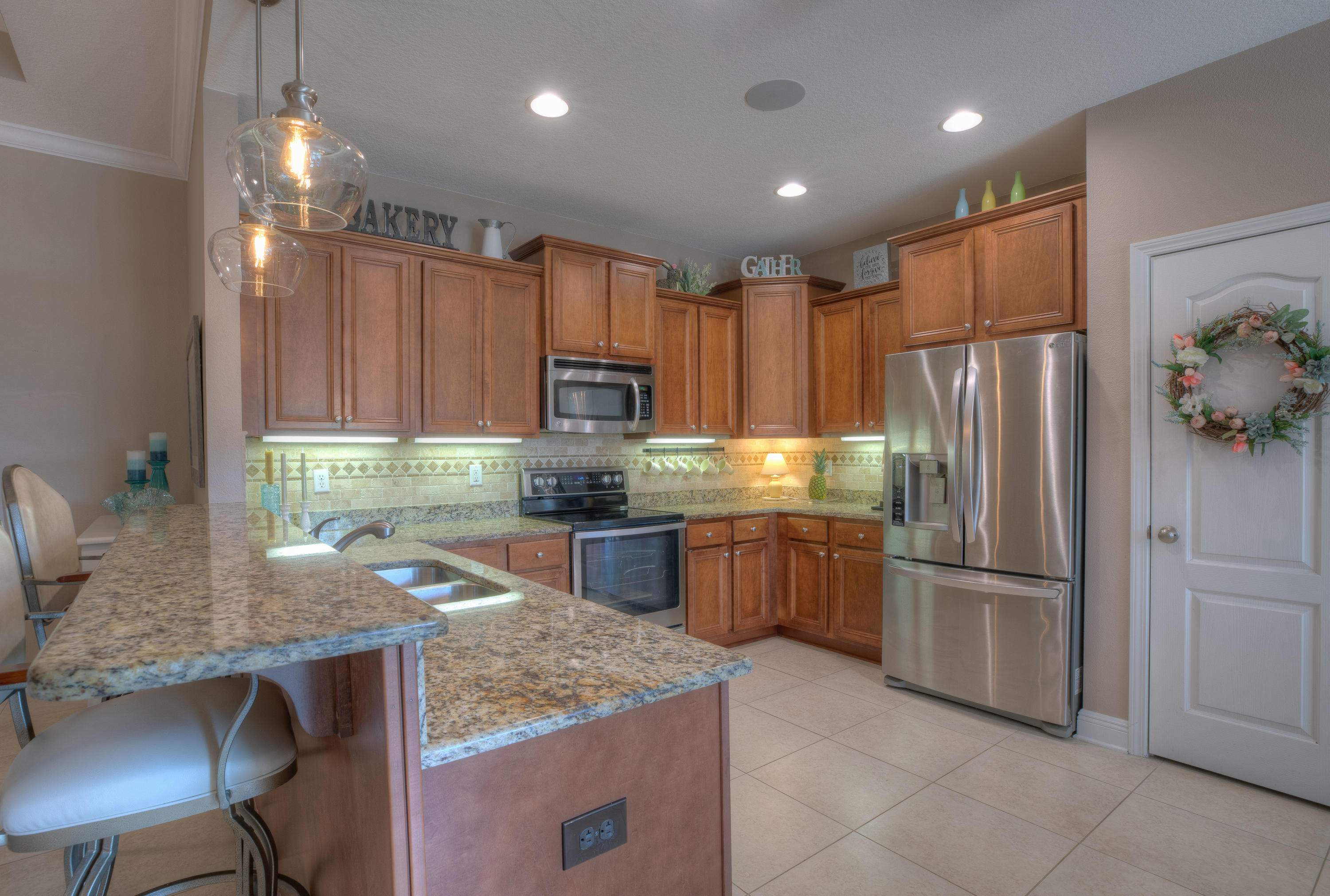 456 Pin Oak Loop Santa Rosa Beach, FL 32459 - Photo 8 of 32 a kitchen with kitchen island granite countertop a table chairs refrigerator and microwave