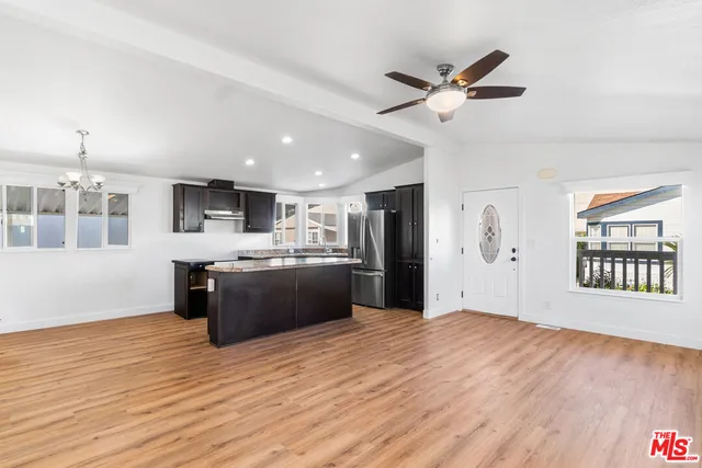 a large white kitchen with stainless steel appliances kitchen island a sink dishwasher a stove and a refrigerator with wooden floor