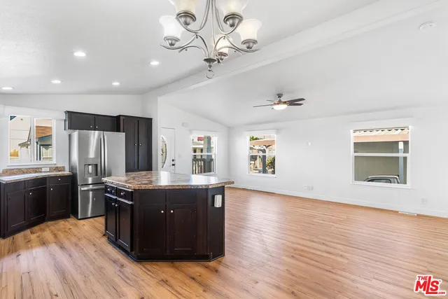 a kitchen with stainless steel appliances granite countertop a stove a sink dishwasher and a refrigerator with wooden floor