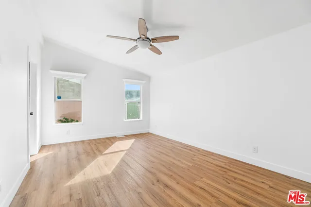 a view of empty room with wooden floor and fan