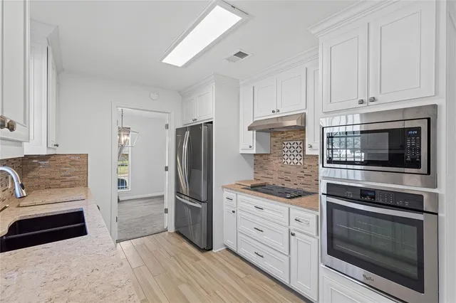 a kitchen with granite countertop white cabinets and stainless steel appliances
