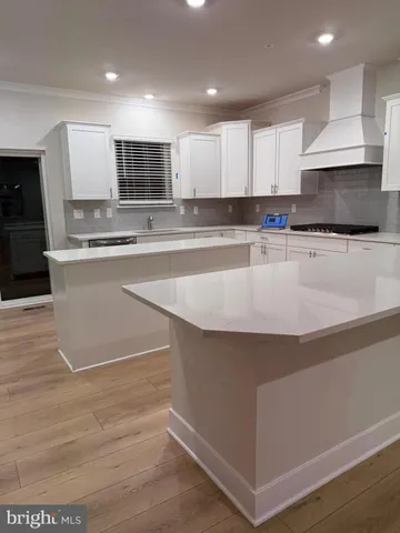 a large kitchen with stainless steel appliances a large counter top and a stove top oven
