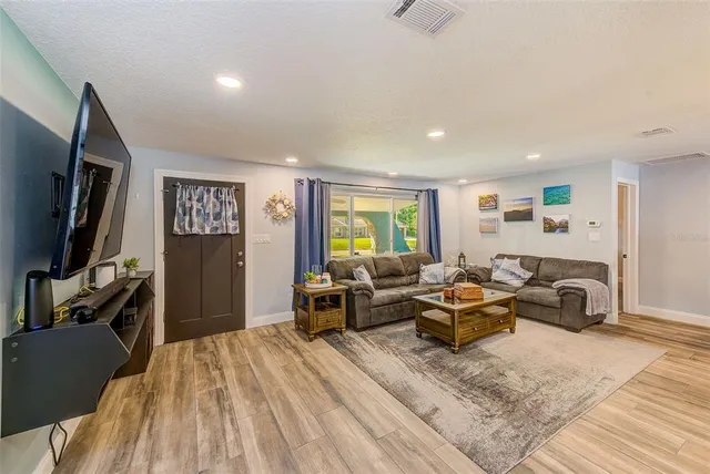 a living room with furniture a flat screen tv and a refrigerator