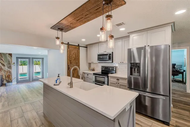 a kitchen view with stainless steel appliances kitchen island granite countertop a sink and cabinets