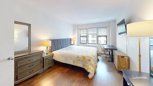 a spacious bedroom with a bed and wooden floor