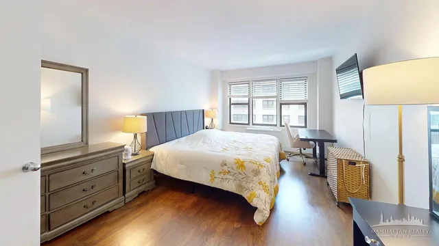 a spacious bedroom with a bed and wooden floor