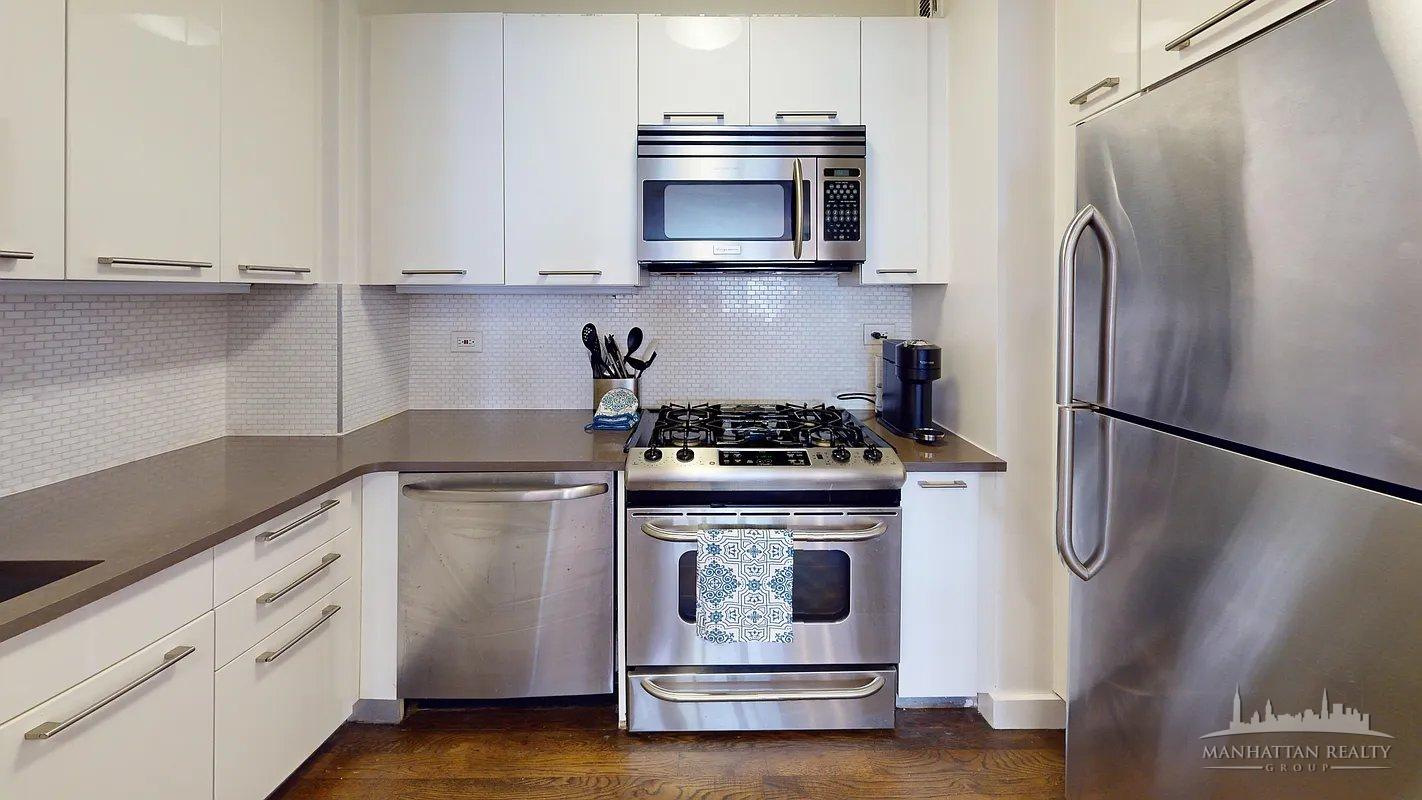 220 East 63rd Street, Unit 8J Manhattan, NY 10023 - Photo 6 of 14 a kitchen with stainless steel appliances a stove a microwave and a refrigerator