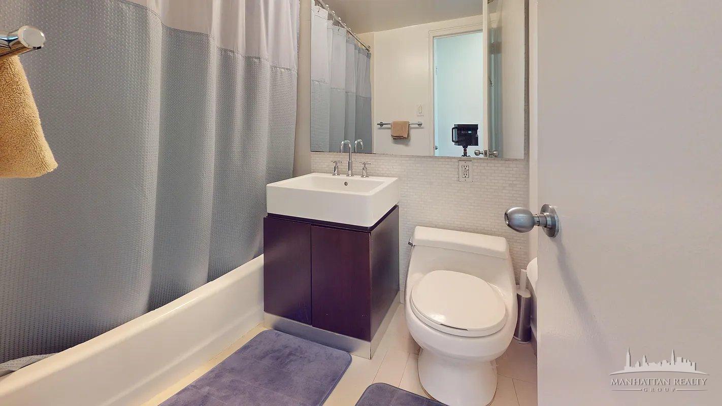 220 East 63rd Street, Unit 8J Manhattan, NY 10023 - Photo 7 of 14 a bathroom with a sink a toilet and a mirror
