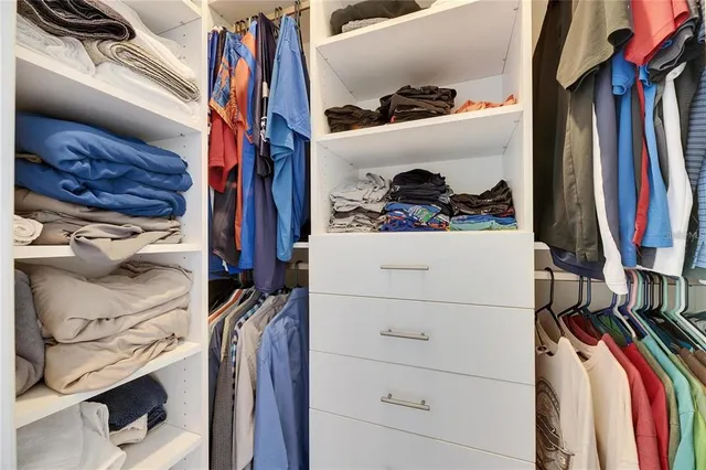 a view of walk in closet with clothes and shoes