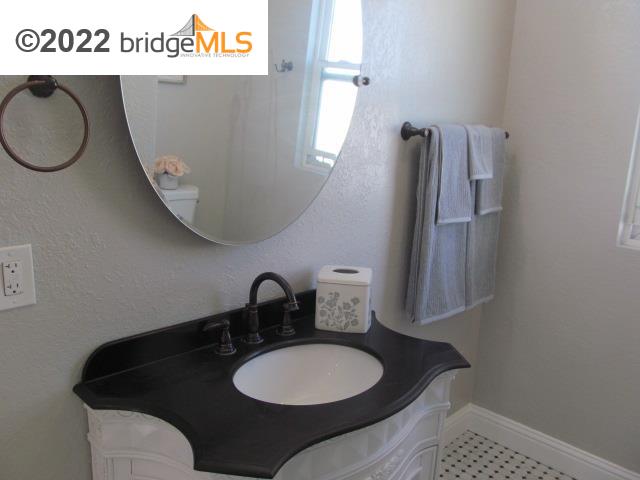 2807 Filbert Street Oakland, CA 94608 - Photo 26 of 29 a bathroom with a granite countertop sink and a mirror