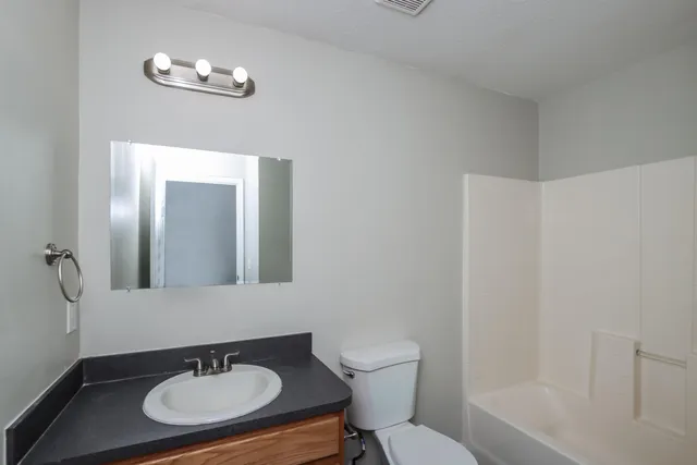 a bathroom with a sink a toilet a mirror and shower