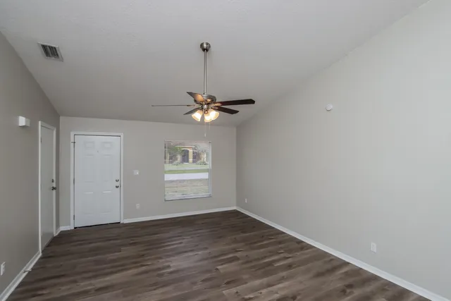 a view of an empty room with a window and wooden floor