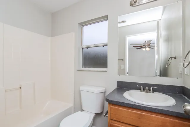 a bathroom with a granite countertop toilet a sink and a mirror