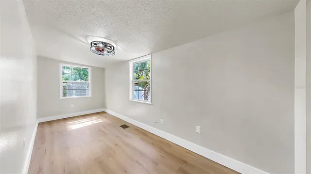 an empty room with windows and fan