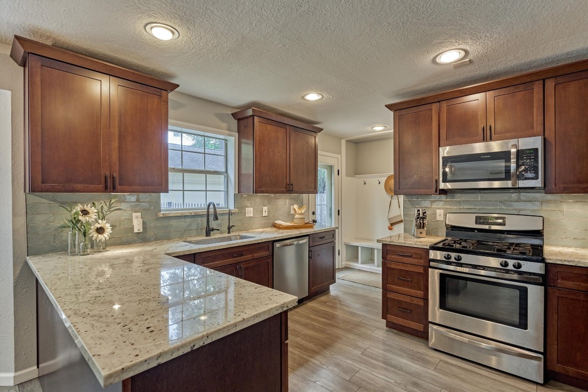 19 Greentwig Place Spring, TX 77381 - Photo 11 of 37 Stainless steel appliances. Stunning backsplash and a peek at mudroom. To right of mudroom and behind the range is a large walk-in pantry.