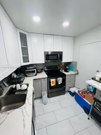 a kitchen with a stove a sink and a refrigerator with wooden floor