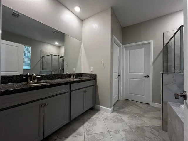 a bathroom with a granite countertop sink and mirror