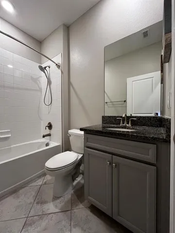 a bathroom with a granite countertop toilet sink and mirror