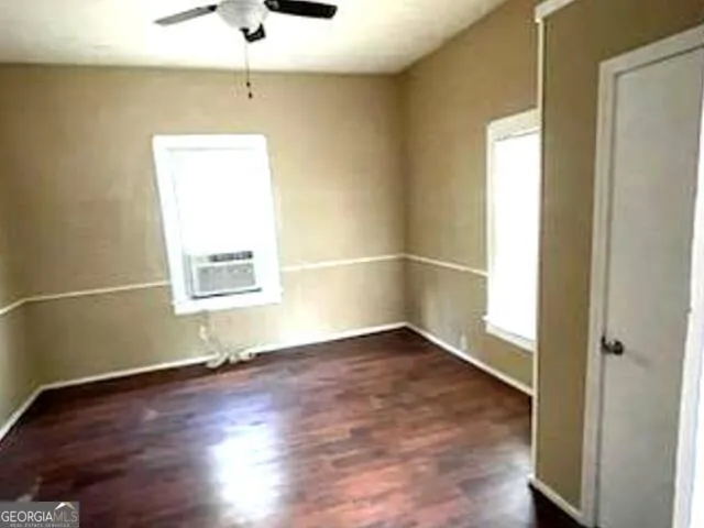 an empty room with wooden floor cabinet and windows