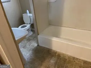 a bathroom with a granite countertop sink and a toilet