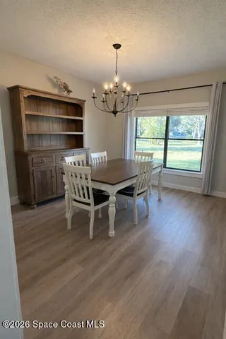 a dining room with furniture a chandelier and wooden floor