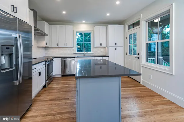 a large kitchen with stainless steel appliances granite countertop a sink and wooden cabinets