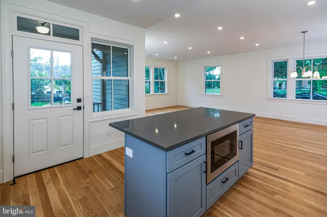 a view of a kitchen with kitchen island a sink wooden floor and a large window