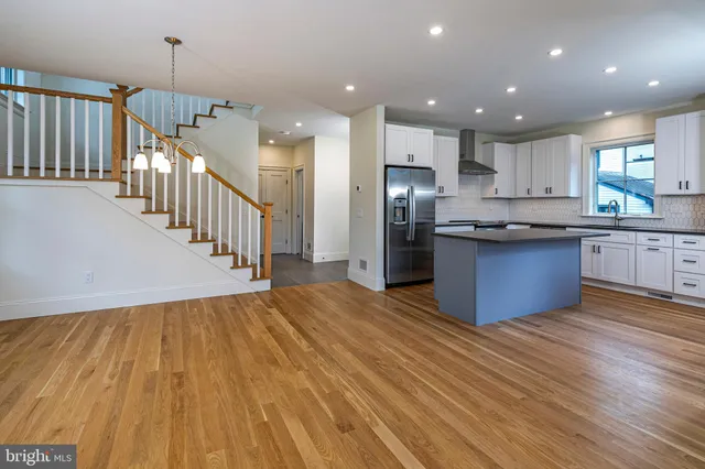 a kitchen with stainless steel appliances kitchen island wooden floors granite and white cabinets