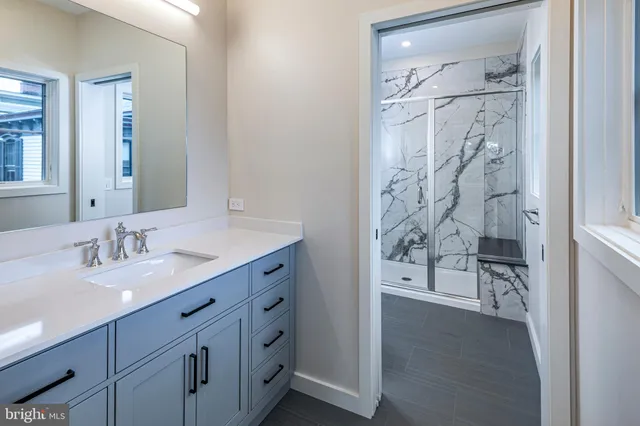 a bathroom with a granite countertop sink a mirror and a shower