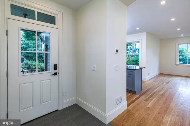 a view of hallway with window and wooden floor