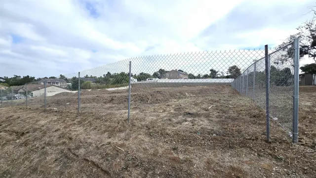 a view of a dry yard with wooden fence