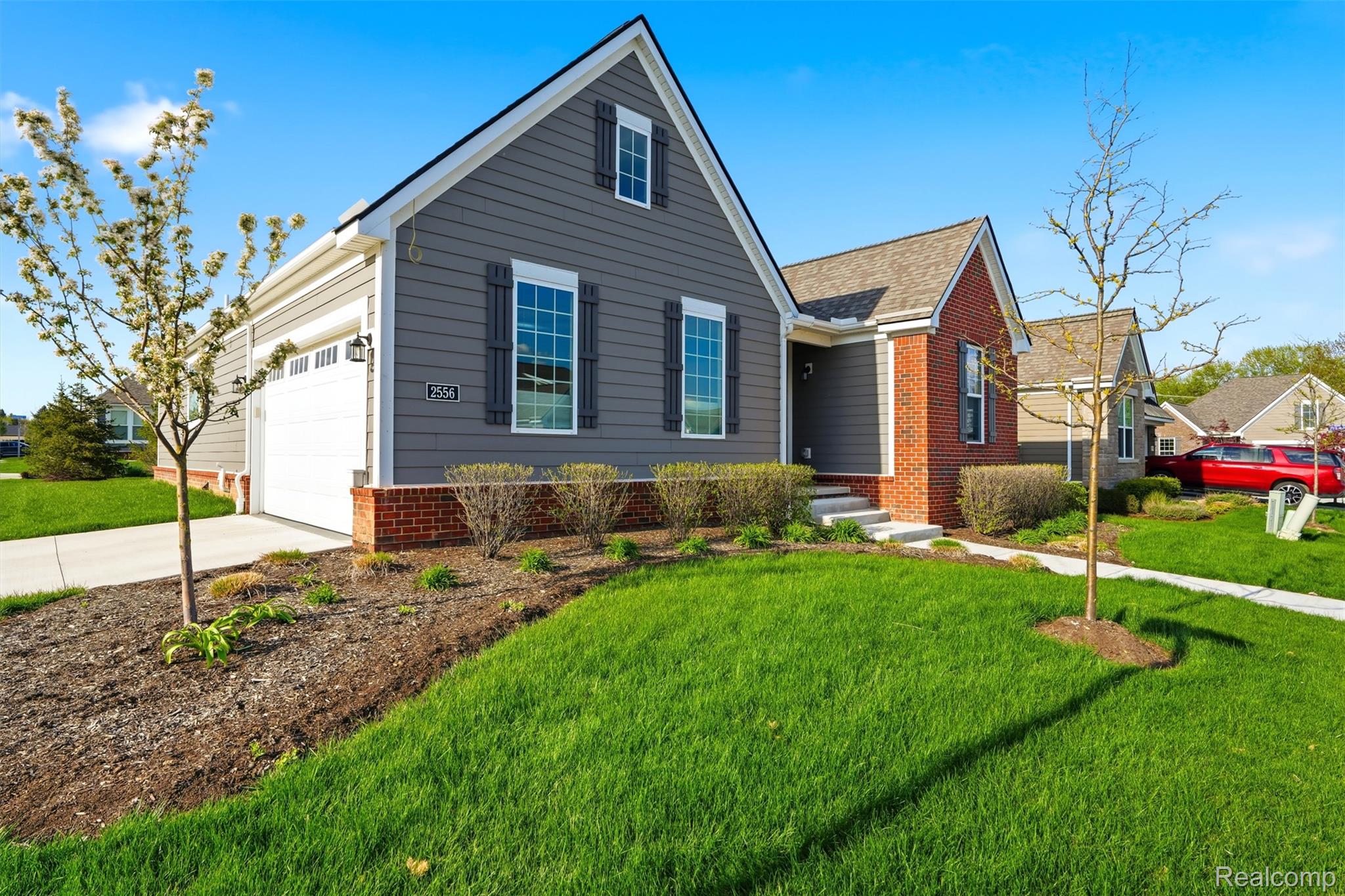 View of front facade featuring a front lawn, brick siding, concrete driveway, and an attached garage