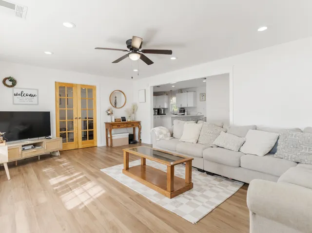 a kitchen with stainless steel appliances a microwave a stove a sink dishwasher a refrigerator and white cabinets with wooden floor