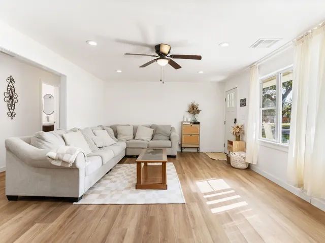 a kitchen with stainless steel appliances a stove a sink a refrigerator white cabinets and wooden floor